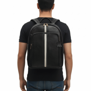  A black leather backpack with a vertical white stripe down the center is shown on the back of a man wearing a black t-shirt and jeans, standing against a white background.